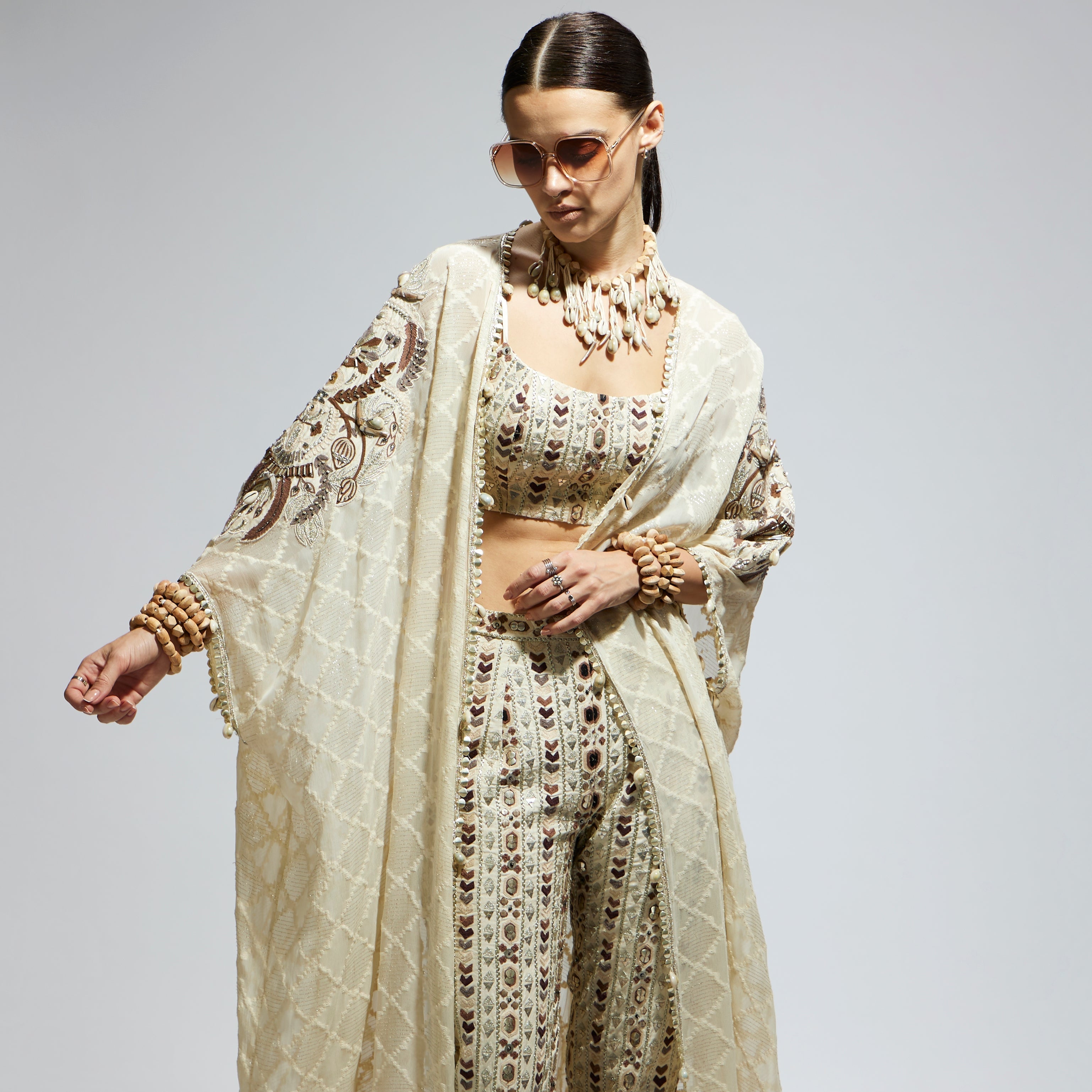 IVORY AZTEC EMBELLISHED CAPE PAIRED WITH HEAVILY EMBELLISHED BUSTIER AND PANTS: SAMSARA