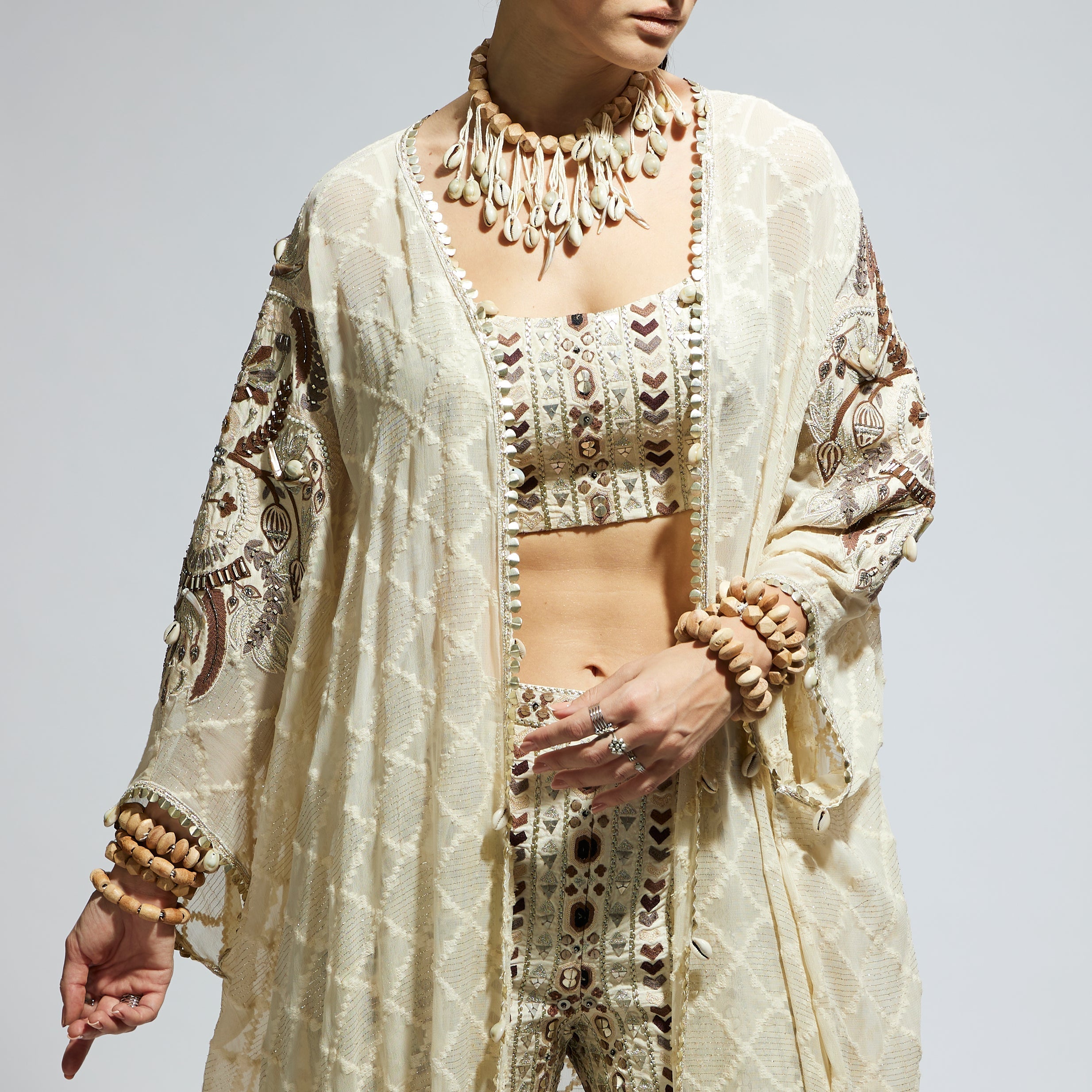 IVORY AZTEC EMBELLISHED CAPE PAIRED WITH HEAVILY EMBELLISHED BUSTIER AND PANTS: SAMSARA