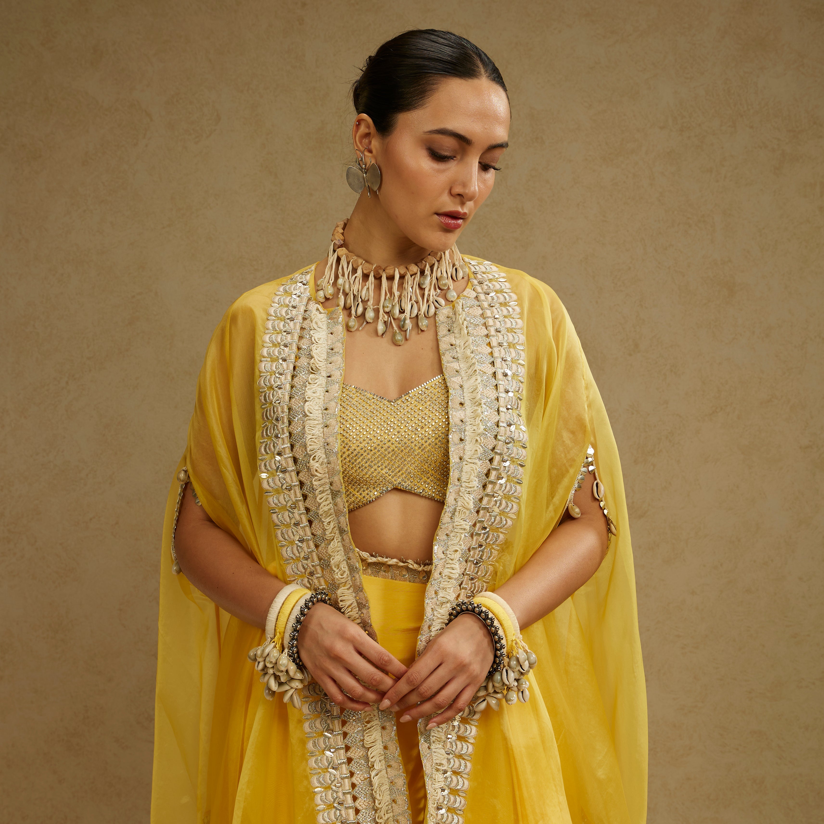 METAL EMBELLISHED BUSTIER PAIRED WITH ORGANZA CAPE AND YELLOW DRAPE SKIRT