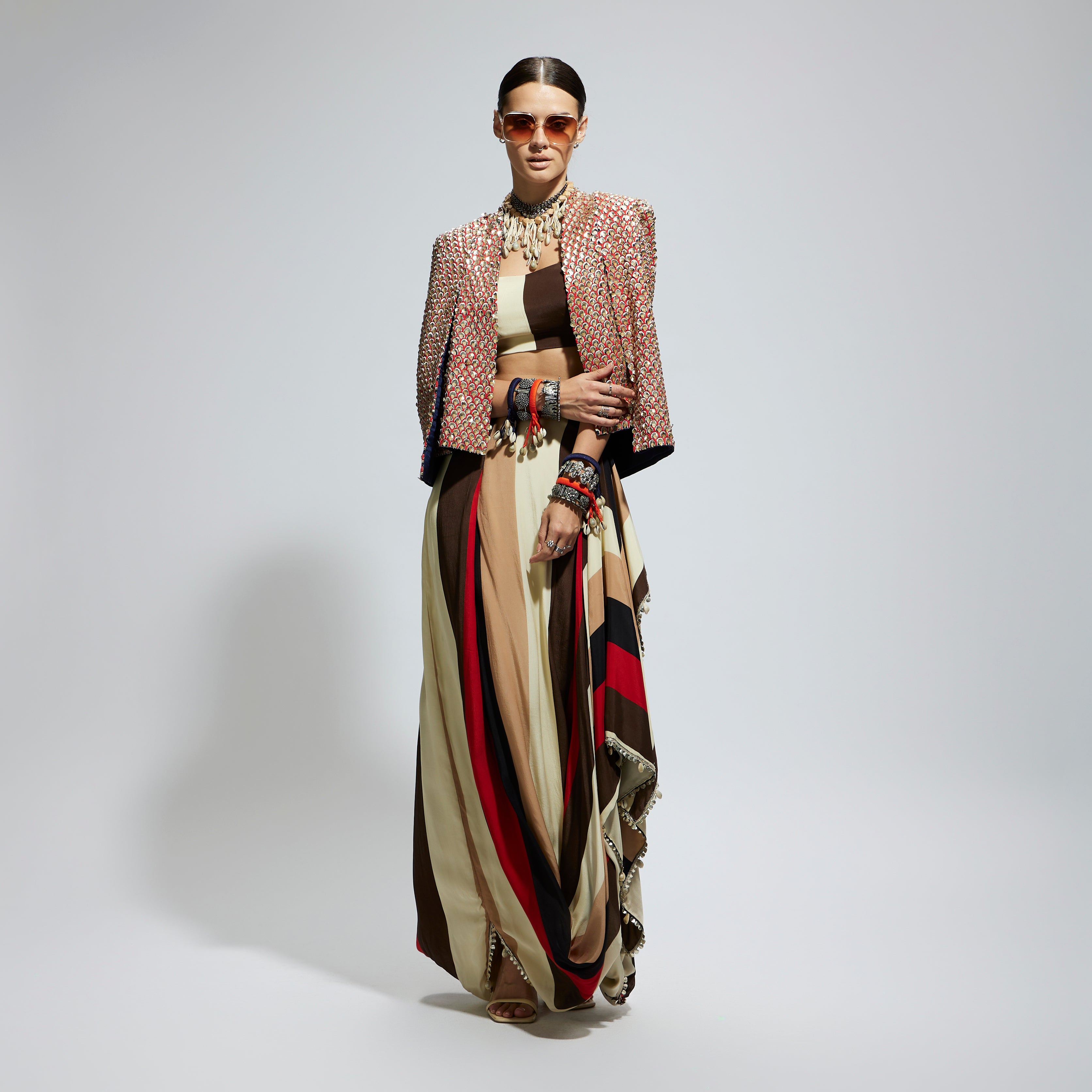 METALLIC EMBELLISHED CAPE JACKET PAIRED WITH STRIPE BUSTIER AND STRIPE DRAPE SKIRT