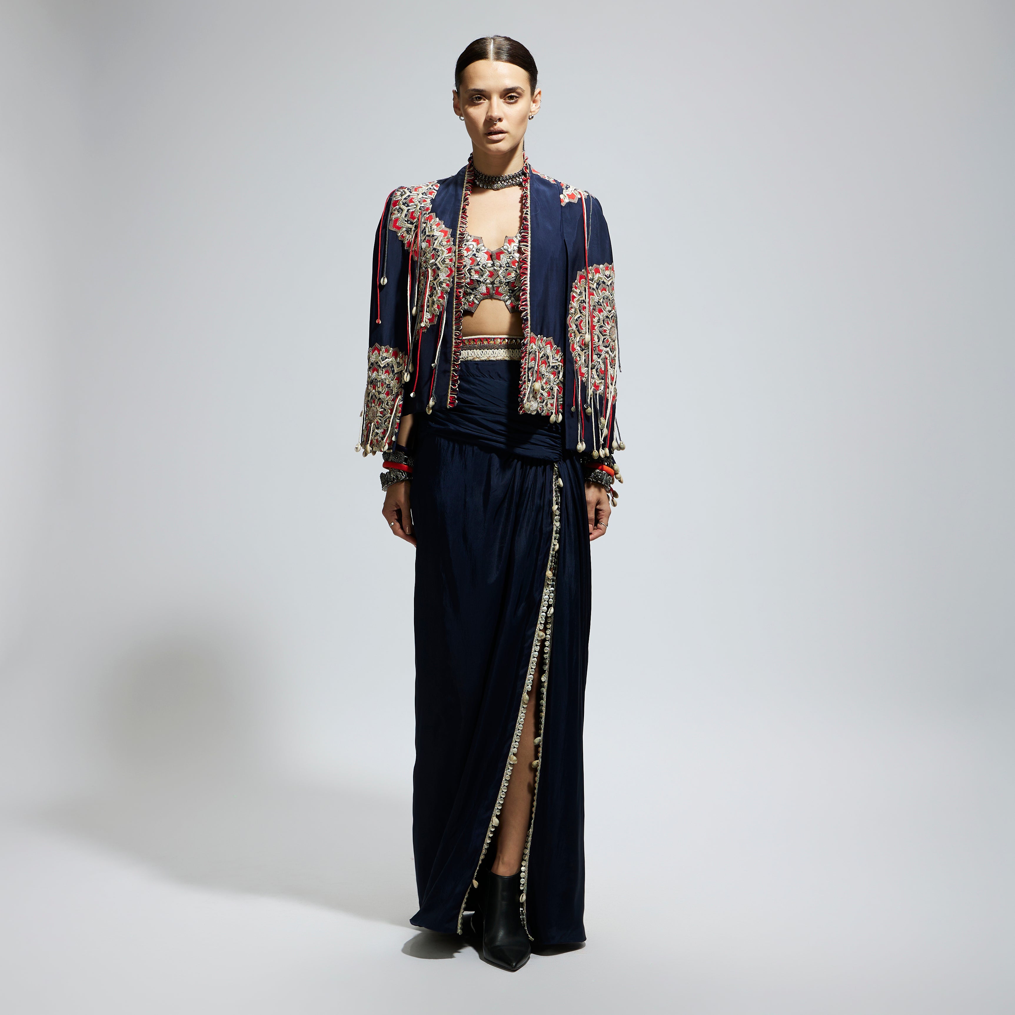 BLUE ASYMETRIC THREADWORK CAPE JACKET PAIRED WITH AN EMBELLISHED BUSTIER AND HIGH SLIT SKIRT