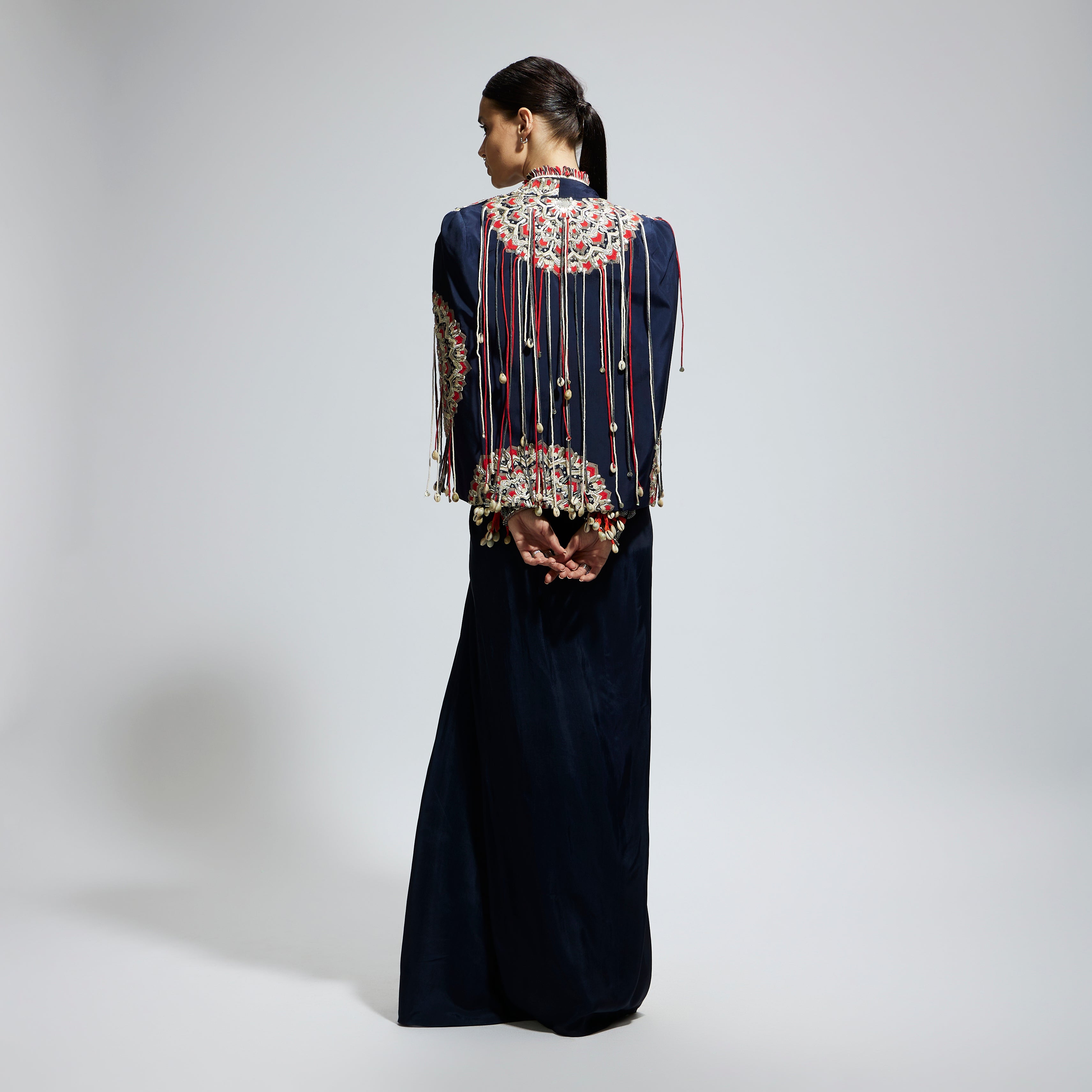 BLUE ASYMETRIC THREADWORK CAPE JACKET PAIRED WITH AN EMBELLISHED BUSTIER AND HIGH SLIT SKIRT