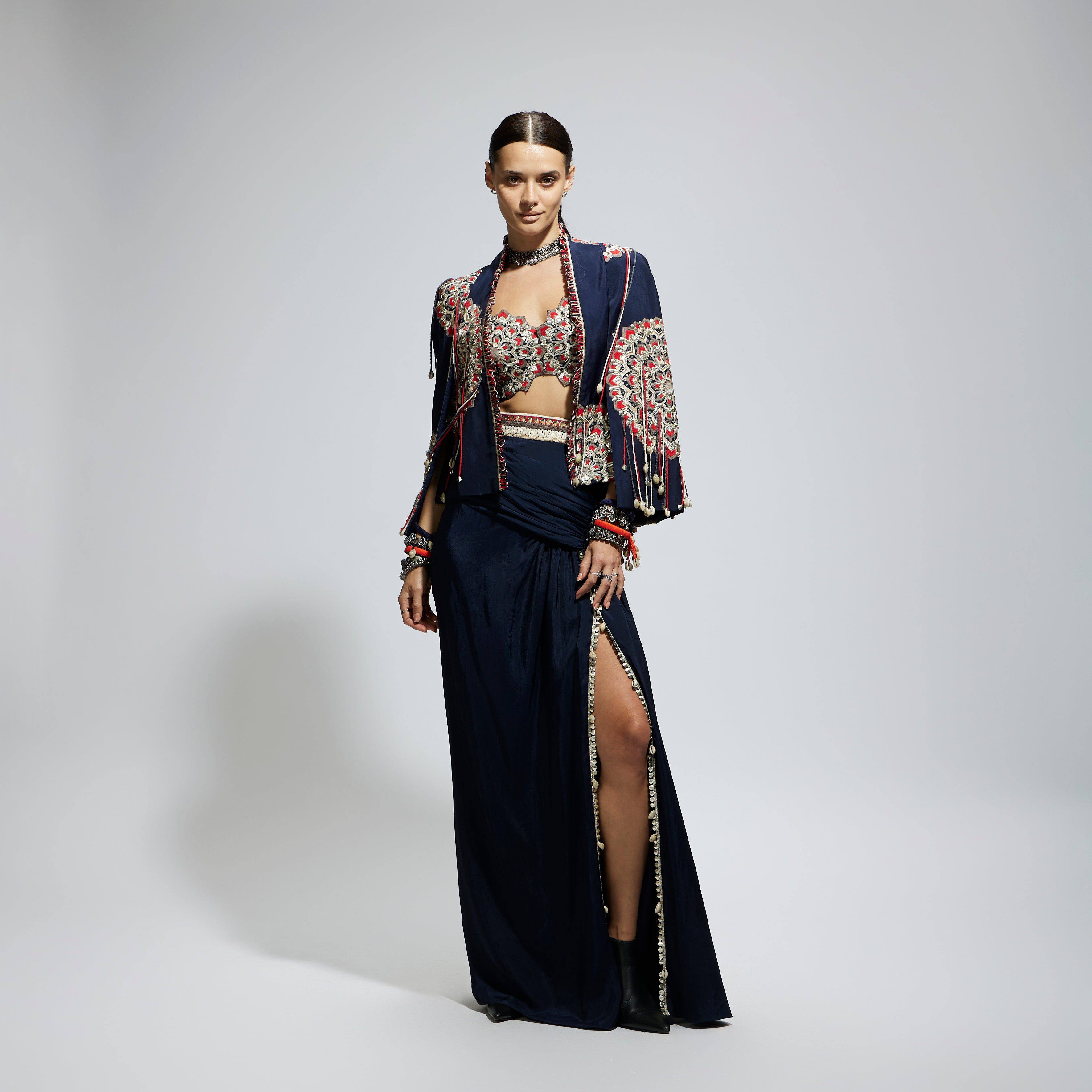 BLUE ASYMETRIC THREADWORK CAPE JACKET PAIRED WITH AN EMBELLISHED BUSTIER AND HIGH SLIT SKIRT