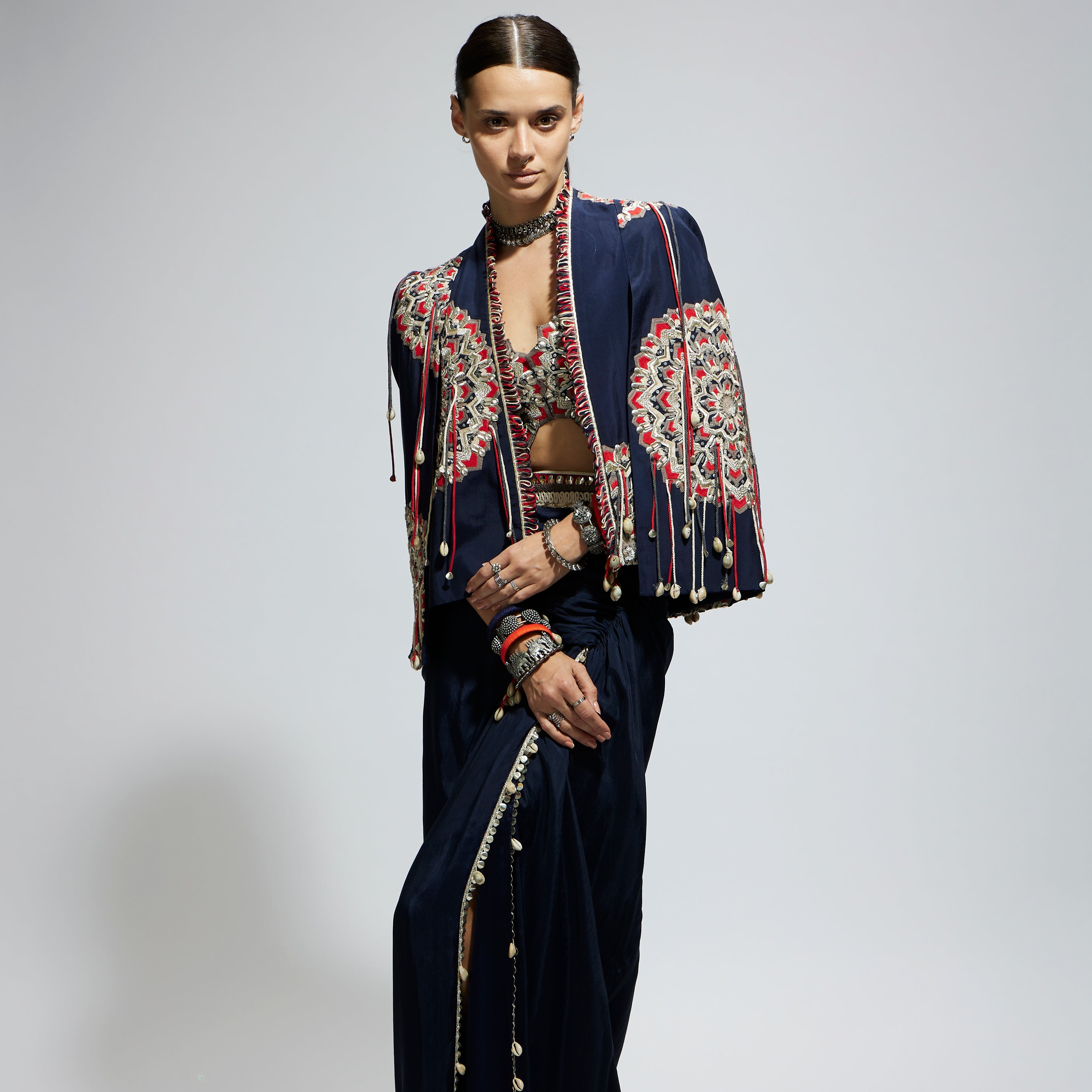 BLUE ASYMETRIC THREADWORK CAPE JACKET PAIRED WITH AN EMBELLISHED BUSTIER AND HIGH SLIT SKIRT