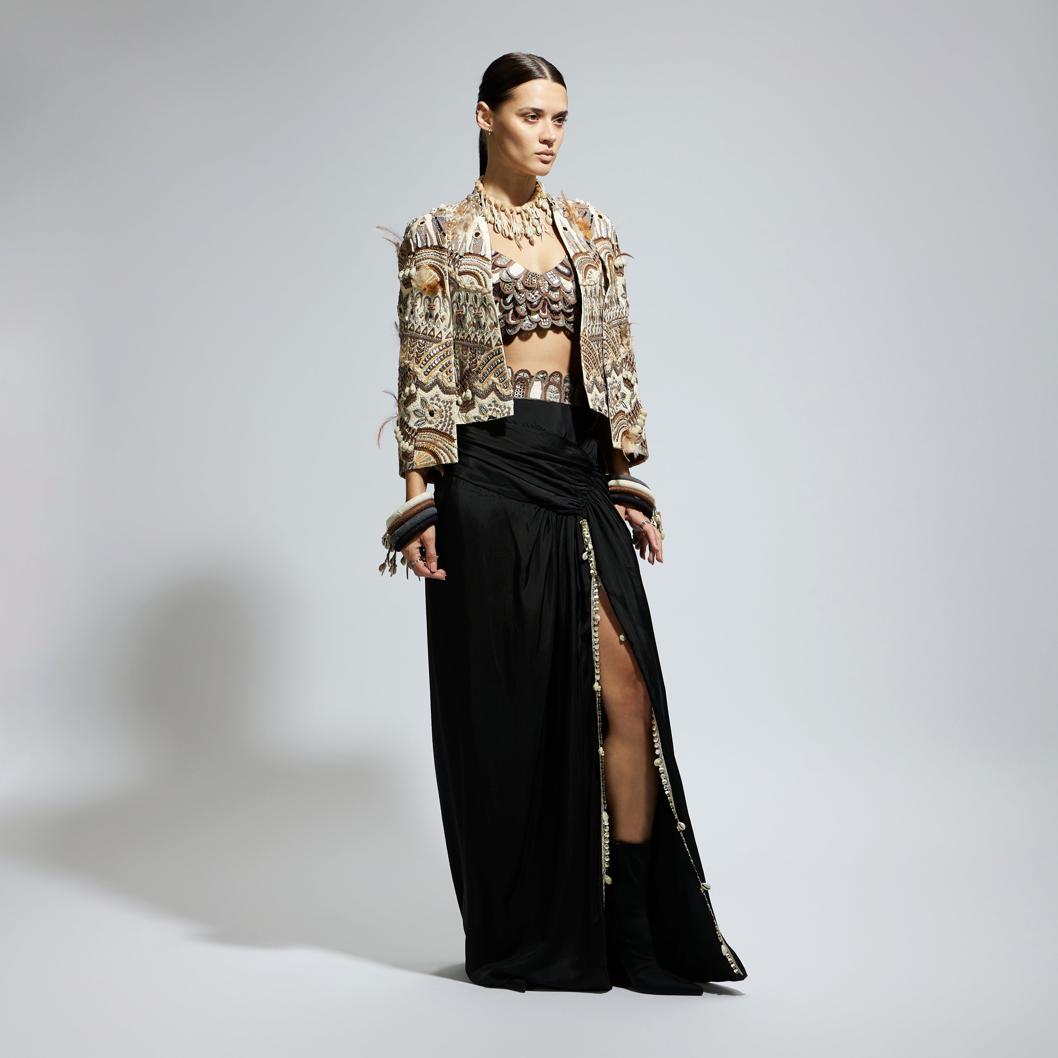 IVORY ABSTRACT FEATHER CAPE JACKET PAIRED WITH 3D SCALLOP BUSTIER AND BLACK HIGH SLIT SKIRT