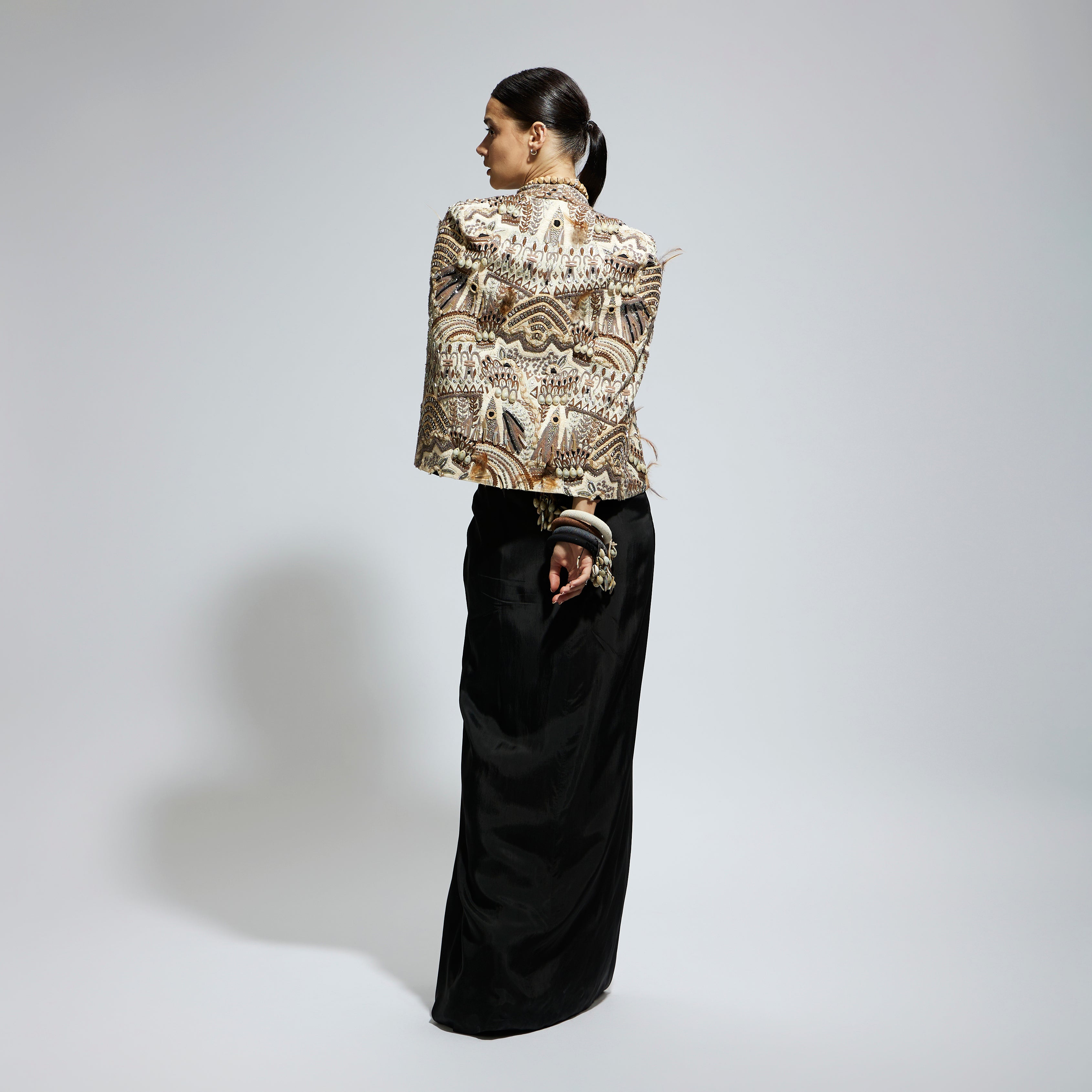 IVORY ABSTRACT FEATHER CAPE JACKET PAIRED WITH 3D SCALLOP BUSTIER AND BLACK HIGH SLIT SKIRT