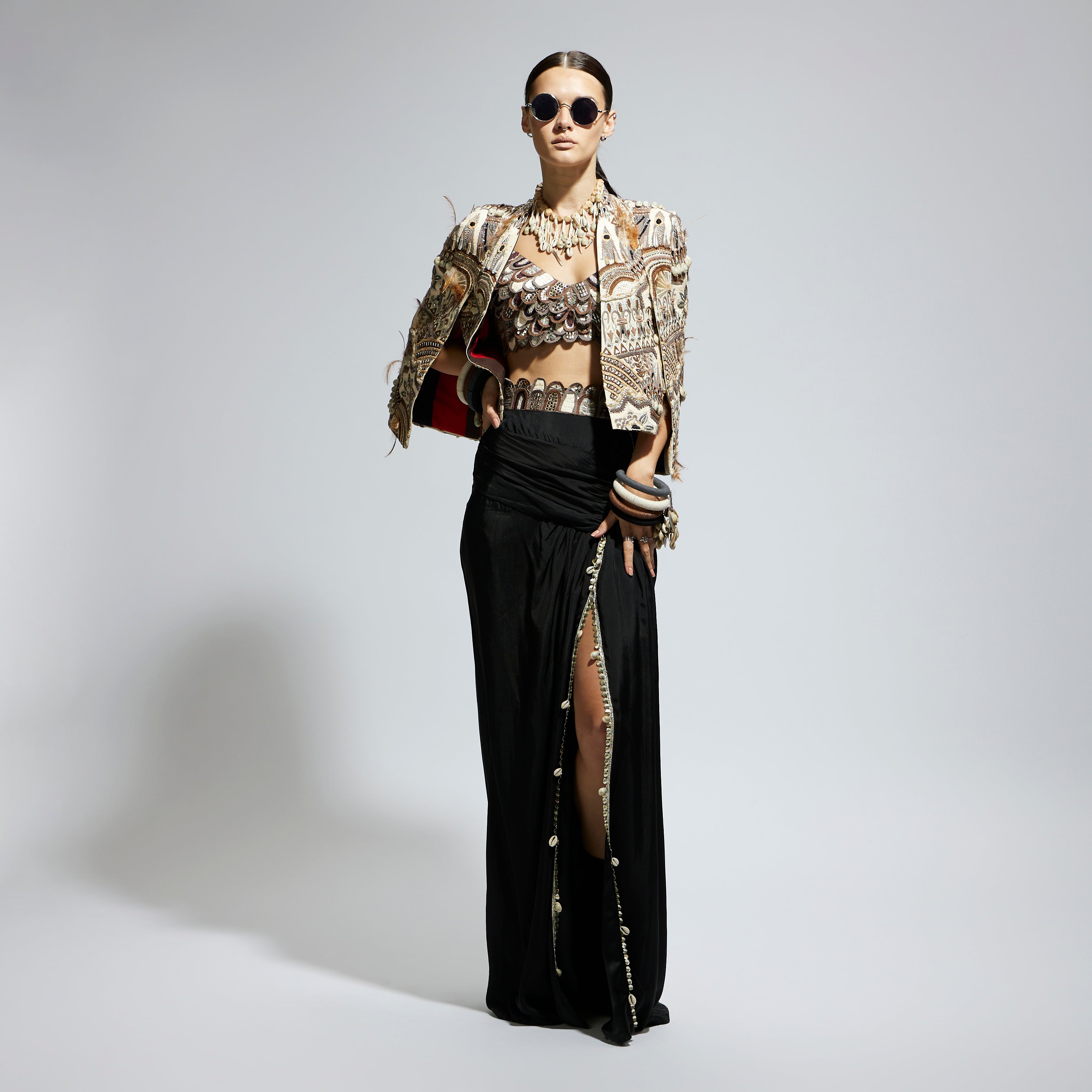 IVORY ABSTRACT FEATHER CAPE JACKET PAIRED WITH 3D SCALLOP BUSTIER AND BLACK HIGH SLIT SKIRT