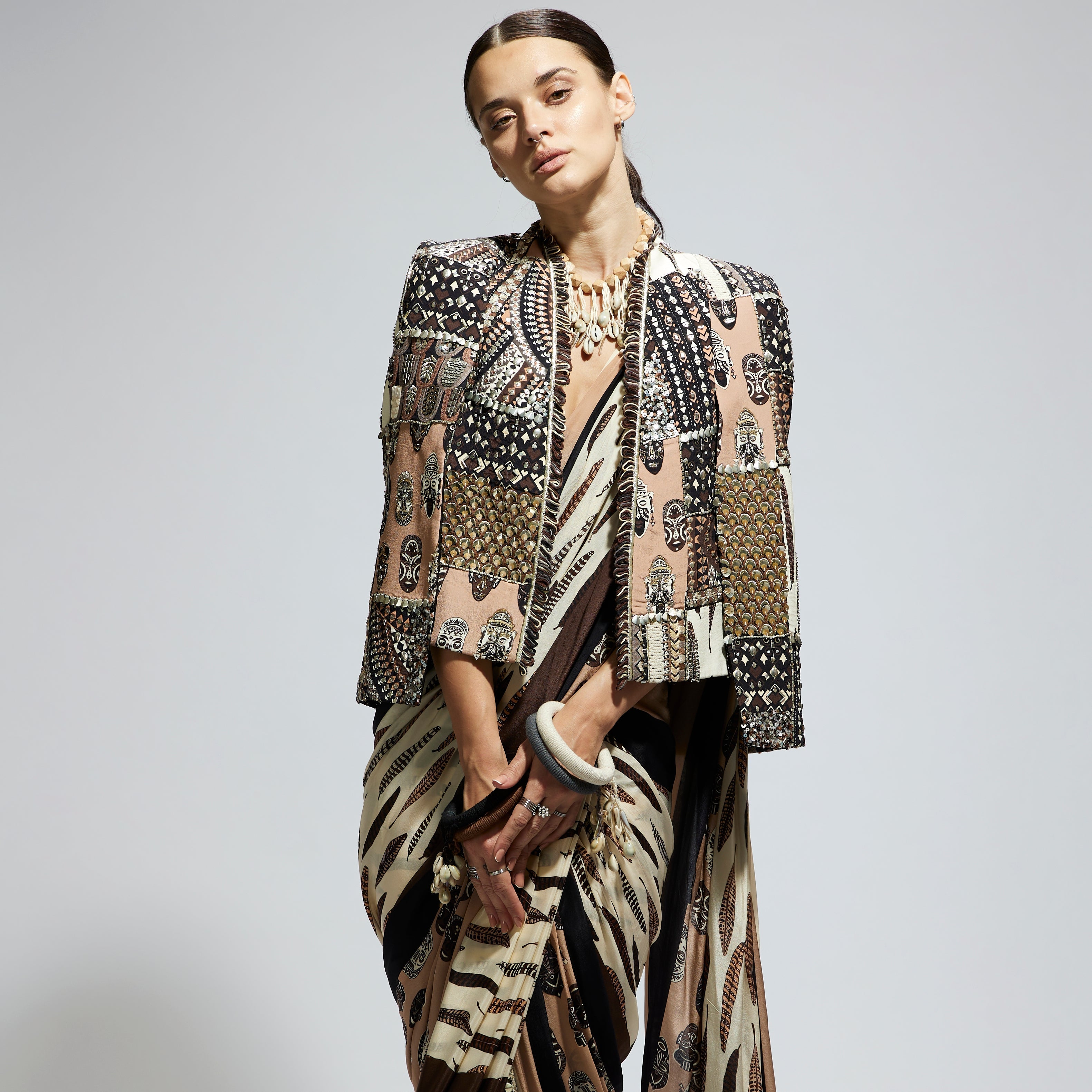 MASK AND FEATHER PRINT CASCADE SAREE PAIRED WITH METALLIC SCALLOP BUSTIER WITH PATCHWORK CAPE JACKET