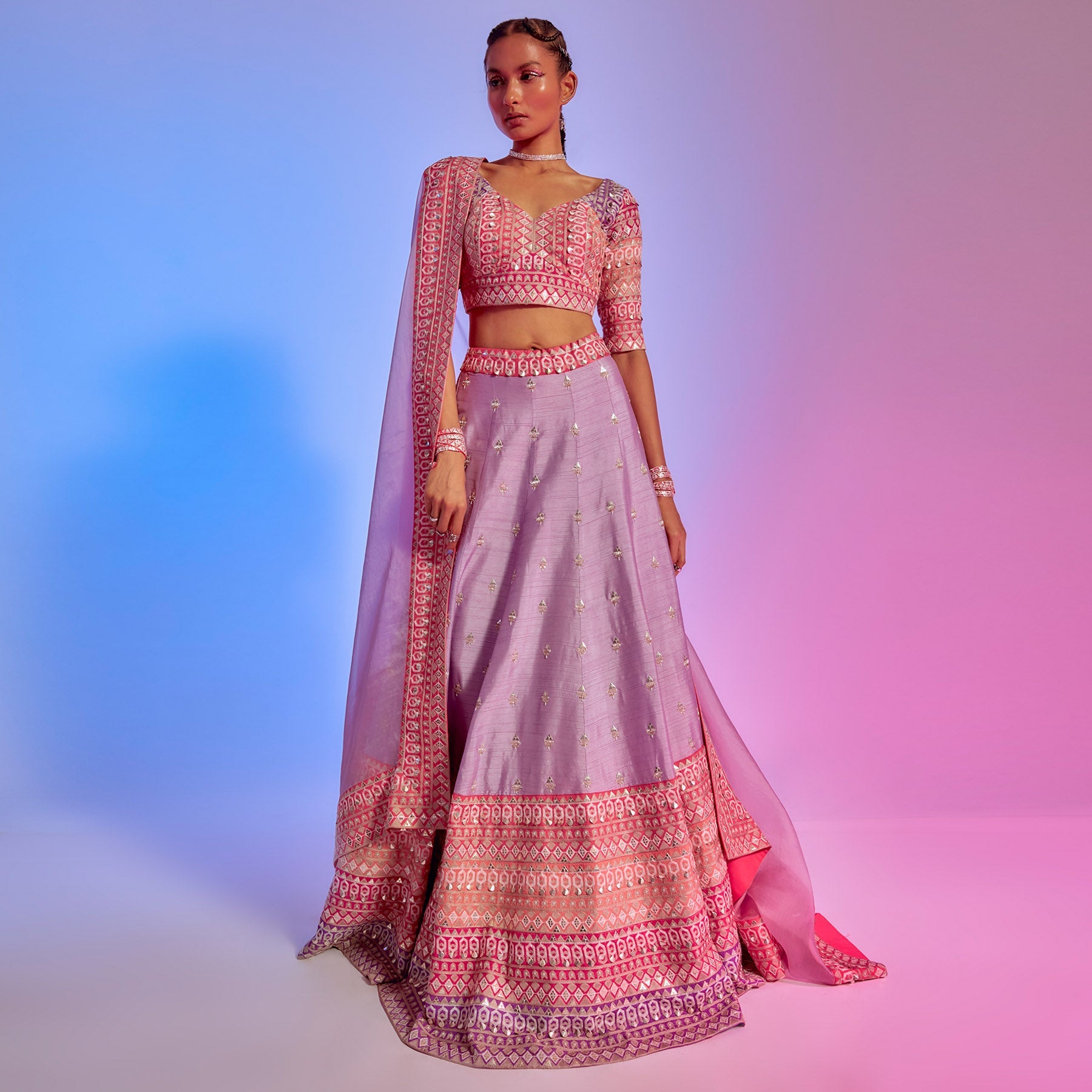 LILAC EMBELLISHED LEHENGA WITH A SUNSET HUES BORDER TEAMED WITH INTRICATE PATCH WORK BLOUSE AND LILAC ORAGNZA DUPATTA